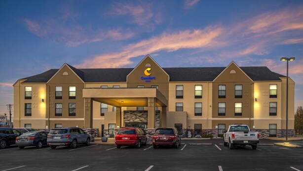 A Comfort Inn hotel with a parking lot, multiple cars, and a clear sky.