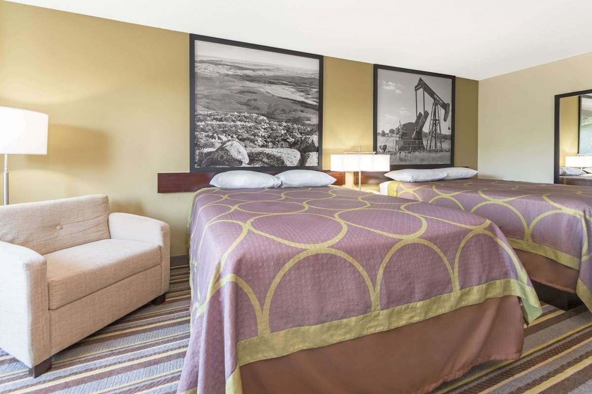 Une chambre d’hôtel avec deux lits, un canapé et deux lampes fixées au mur.