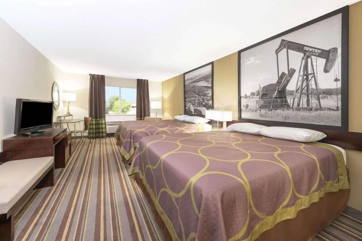 Une chambre d’hôtel avec un lit, une télévision, un bureau et une fenêtre avec des rideaux.