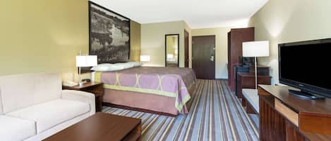 A hotel room with a bed, a sofa, a TV, a desk, and a large painting on the wall.