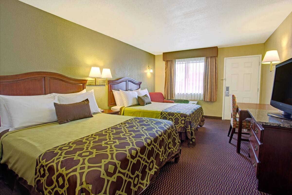 Une chambre d’hôtel avec deux lits, un bureau avec une télévision et une chaise.
