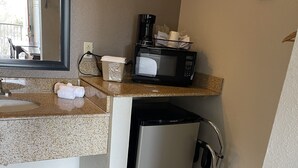 A compact kitchen with a granite countertop, a coffee maker, a microwave, and a compact refrigerator. - Travelodge by Wyndham Tucson AZ (Tucson)