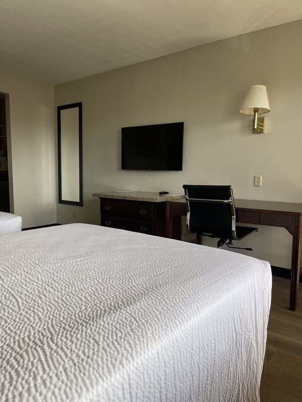 A hotel room with a large bed, a desk, a chair, a television, and a lamp. - Travelodge by Wyndham Tucson AZ (Tucson)