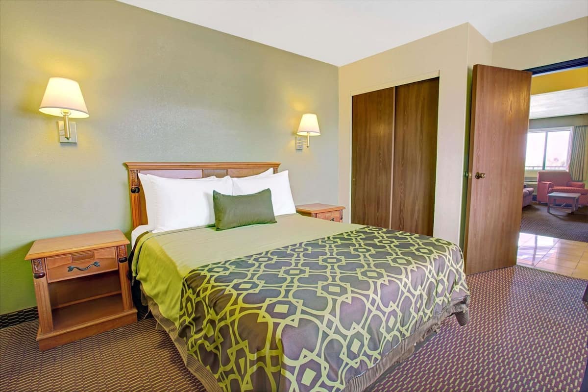 Une chambre d’hôtel comprenant un lit, deux lampes de chevet, une table de nuit en bois, une armoire et une vue sur l’extérieur.