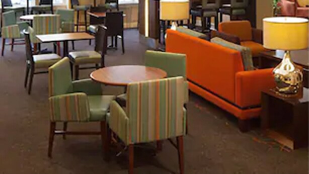 A hotel lobby with seating areas, tables, and a clock on the wall. - Residence Inn by Marriott St Louis Airport (Earth City)