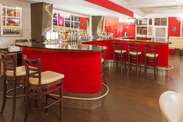 A bar area with a red counter, multiple bar stools, and a variety of bottles and glasses. - Dormero Hotel Plauen (Plauen)