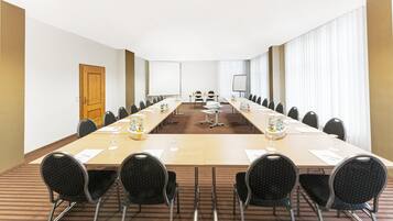 A conference room with a long table, chairs, a projector screen, and a whiteboard.