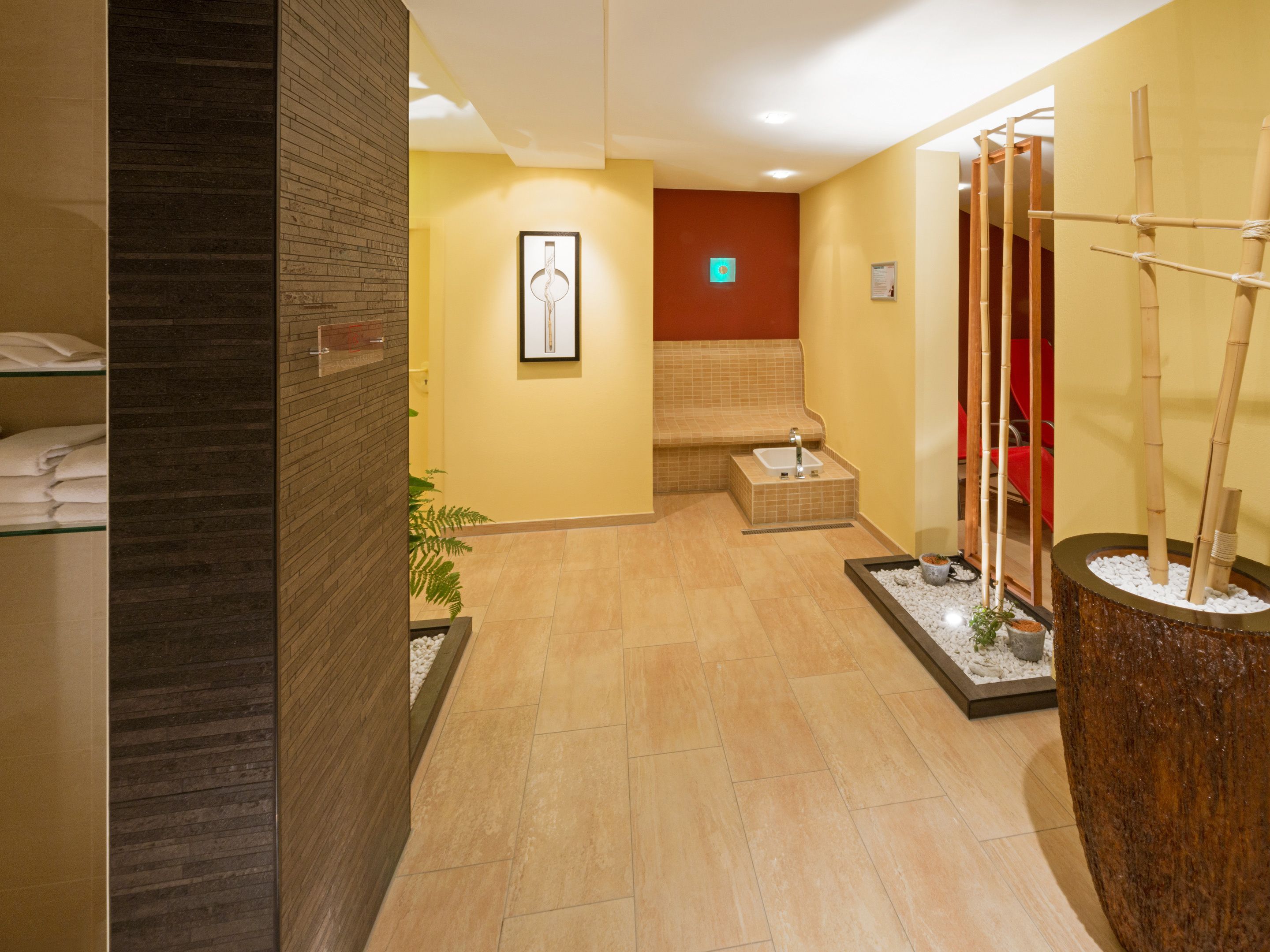 A hotel lobby with a reception desk, a seating area, and a decorative plant arrangement.