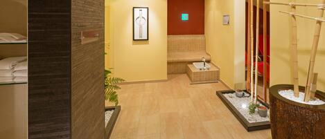 A hotel lobby with a reception desk, a seating area, and a decorative plant arrangement.
