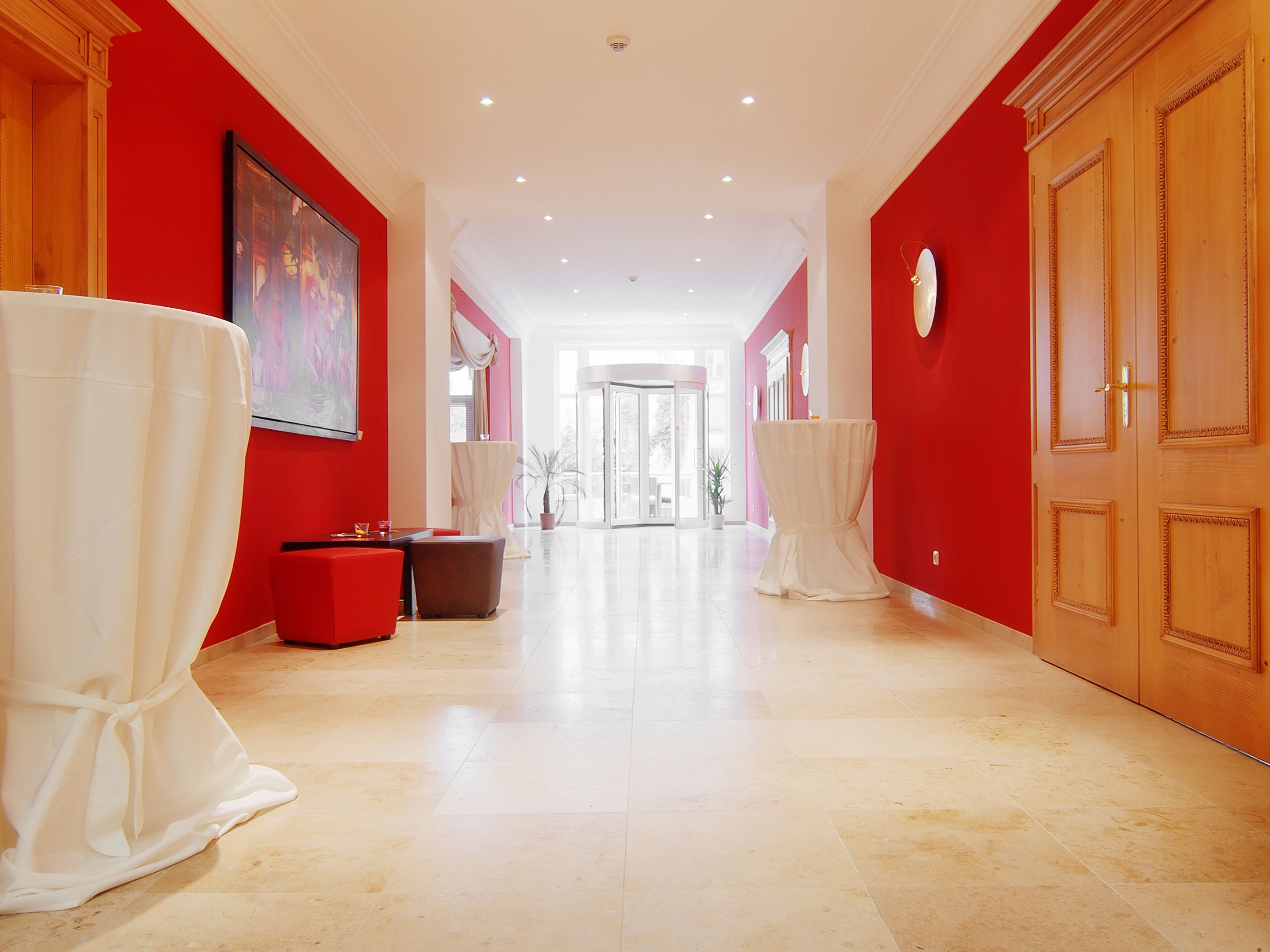 Corredor de hotel com paredes vermelhas, teto branco e chão de azulejos.