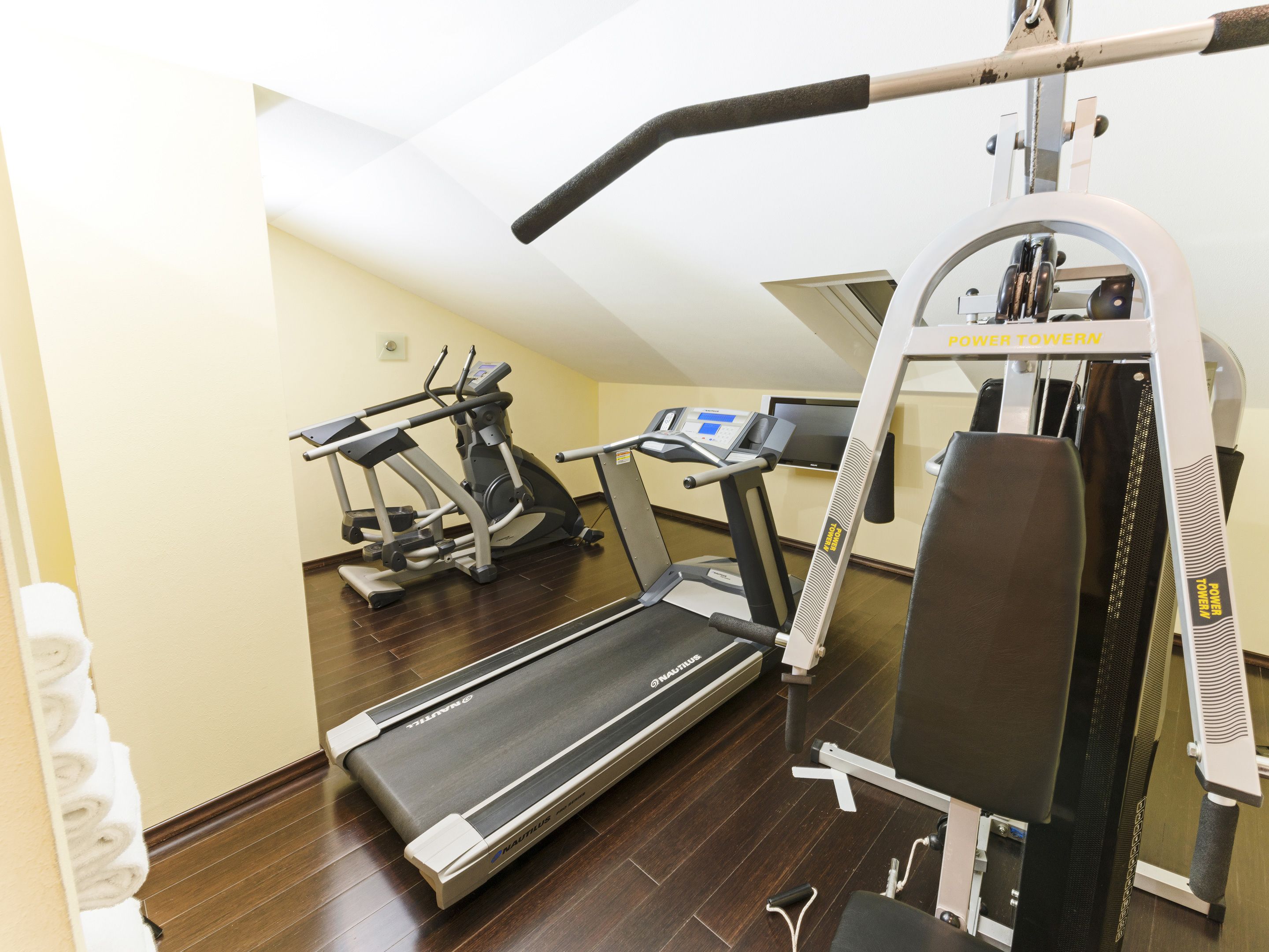 Un gimnasio con cintas de correr, una bicicleta estática y una máquina de remo.