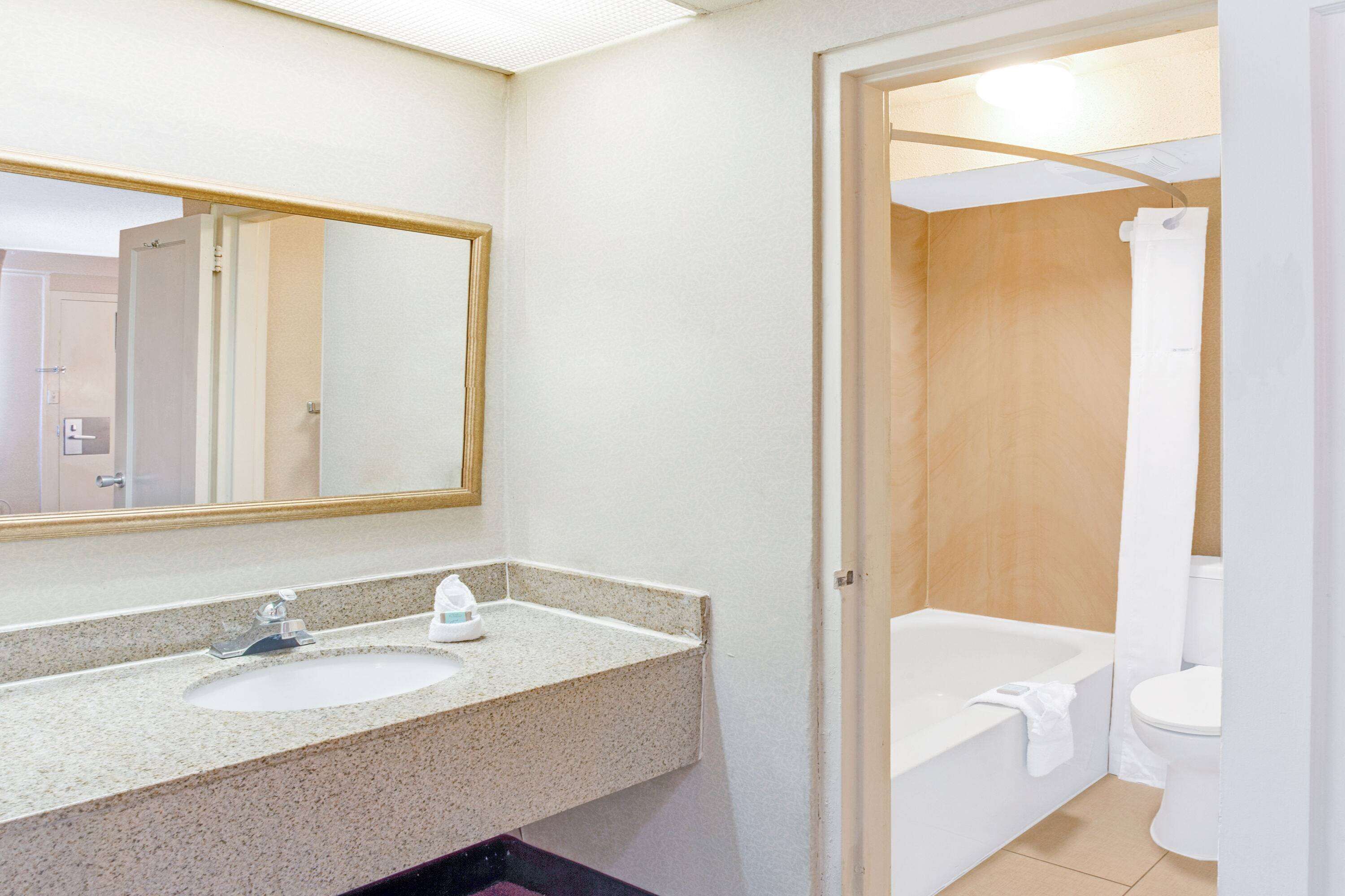 A bathroom with a sink, mirror, and bathtub.