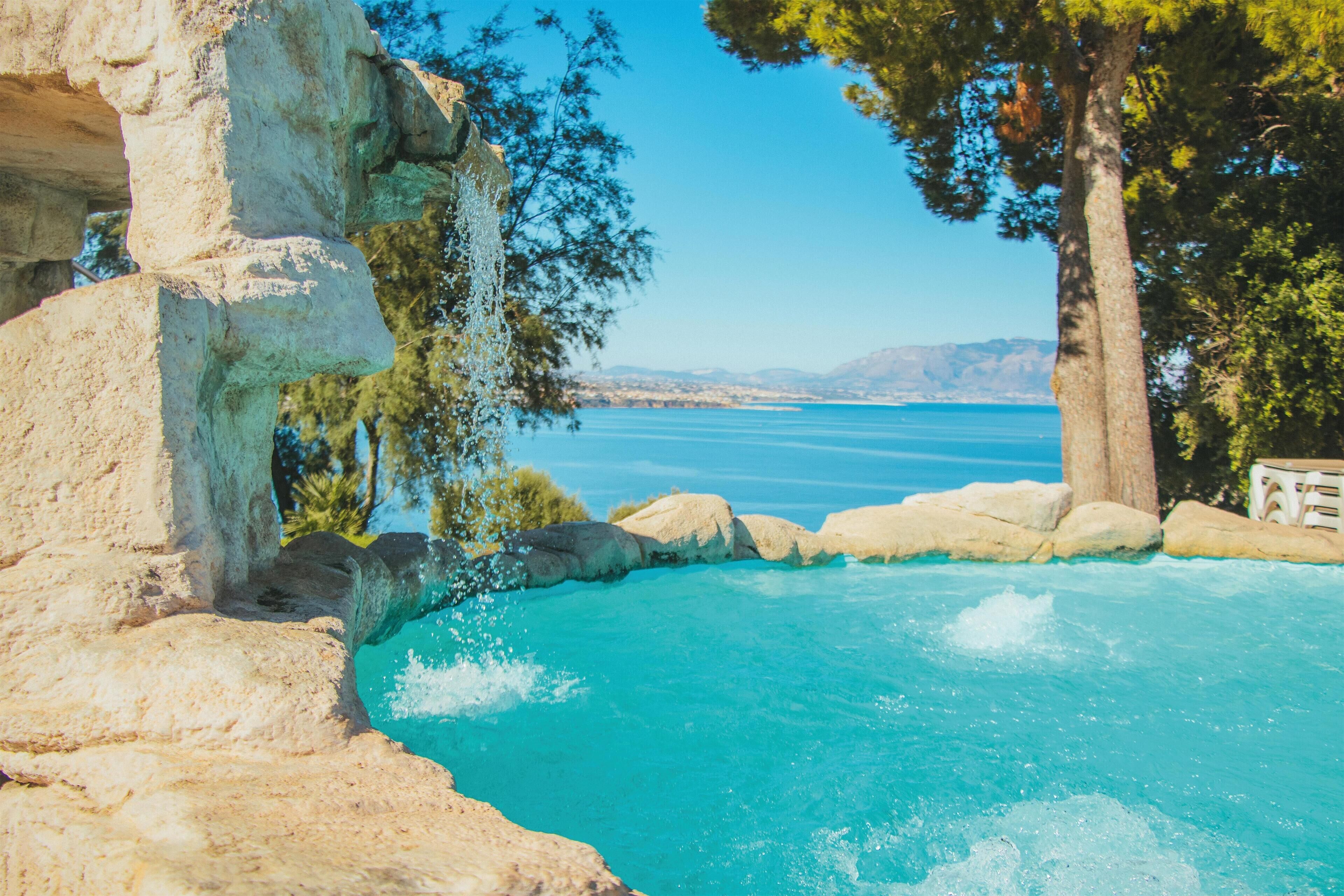 Una piscina al aire libre de temporada, sombrillas, tumbonas
