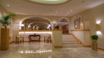Un hall amplio con mostrador de recepción, zona de estar y escalera que lleva a los pisos superiores.