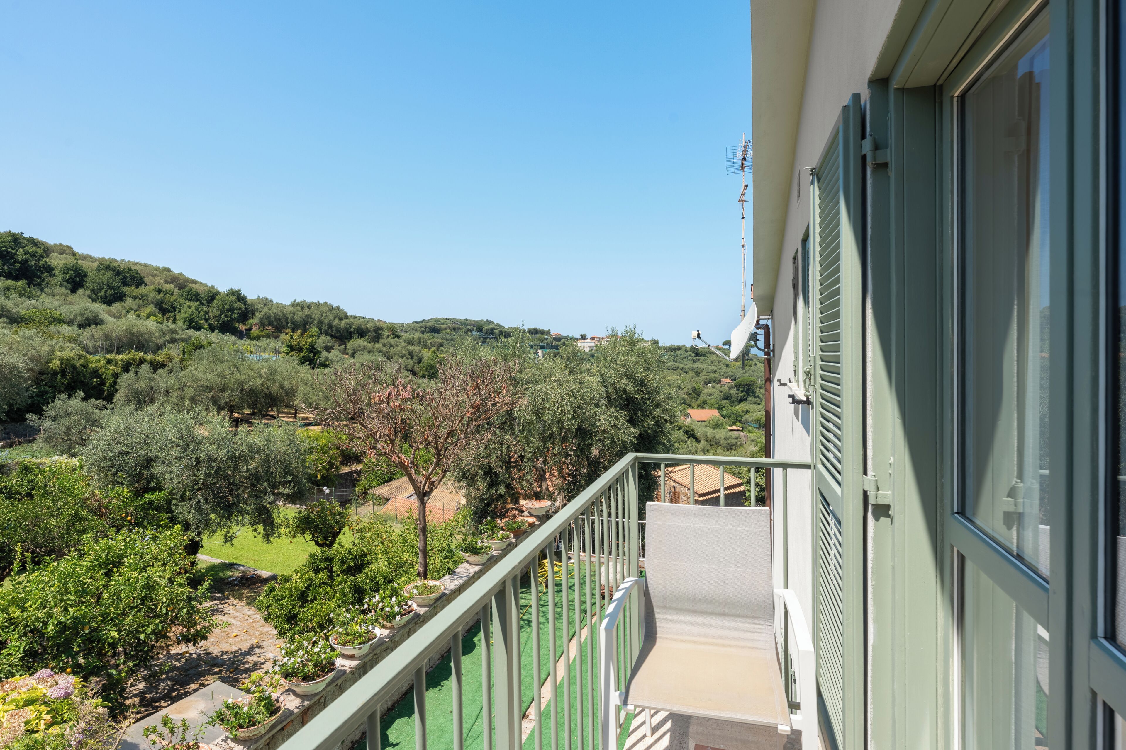 A balcony with a view of a green landscape and a hill in the distance.