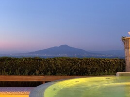Una piscina con vistas a una montaña y luces de la ciudad al fondo.