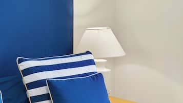 Una cama con ropa de cama y almohadas azules, una lámpara de noche y una mesita de noche de madera.