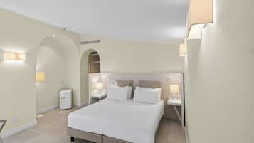 Camera d'albergo con un letto grande, due comodini con lampade, un piccolo elettrodomestico bianco e un riscaldatore a parete.