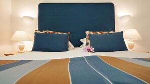Relax in a spacious room with a large bed, geometric-patterned bedspread, and two bedside lamps.