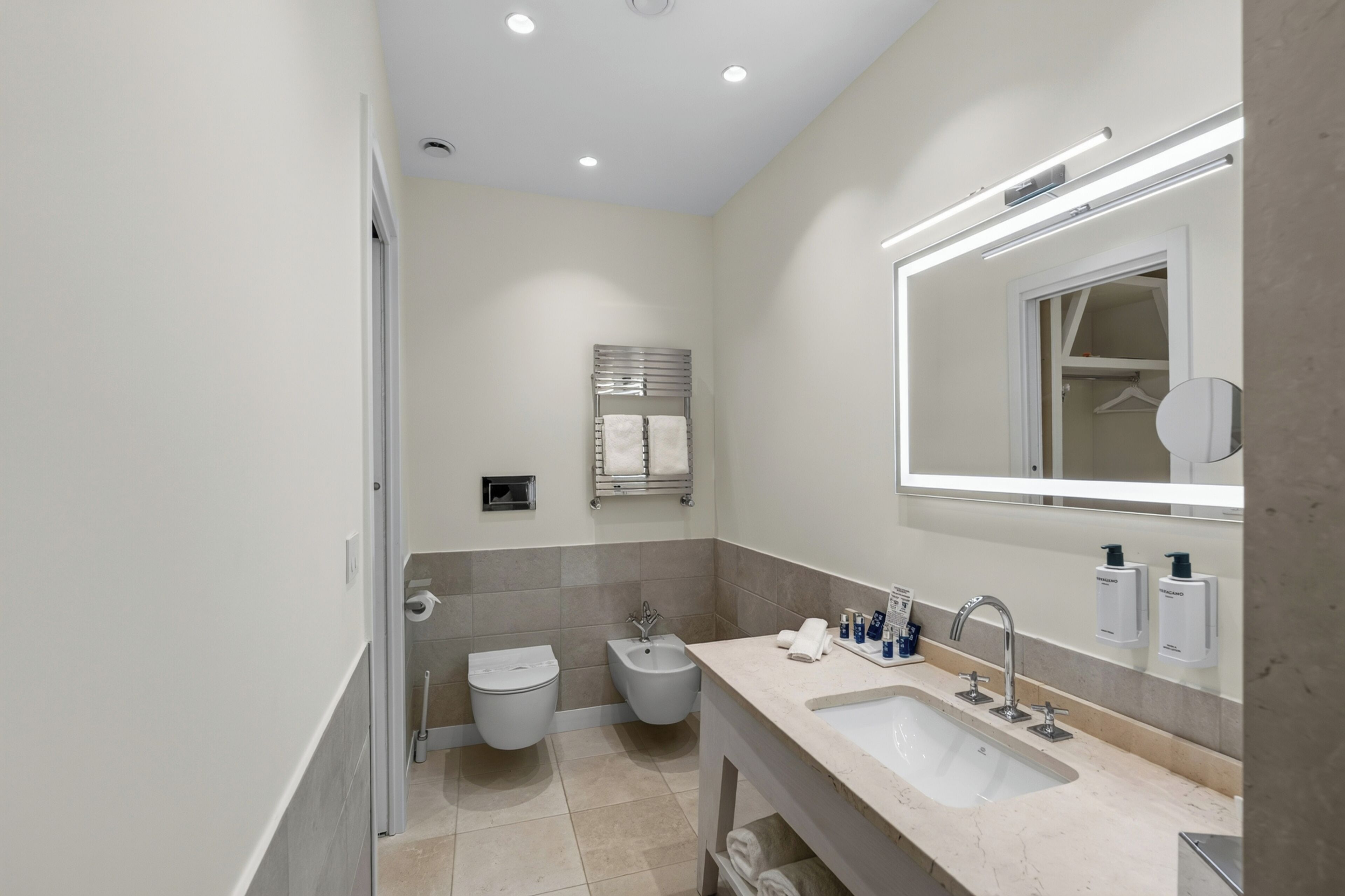 Un baño moderno con lavamanos, espejo, toallero y retrete.