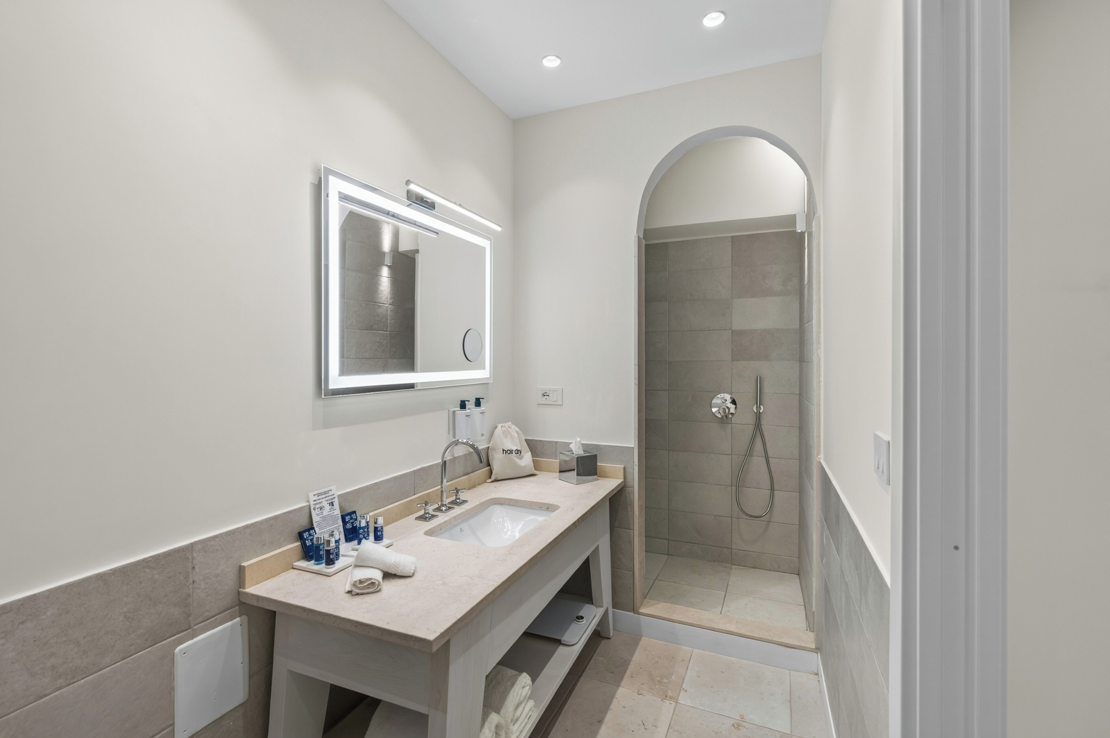 A modern bathroom with a double sink vanity, a mirror, and a shower area.