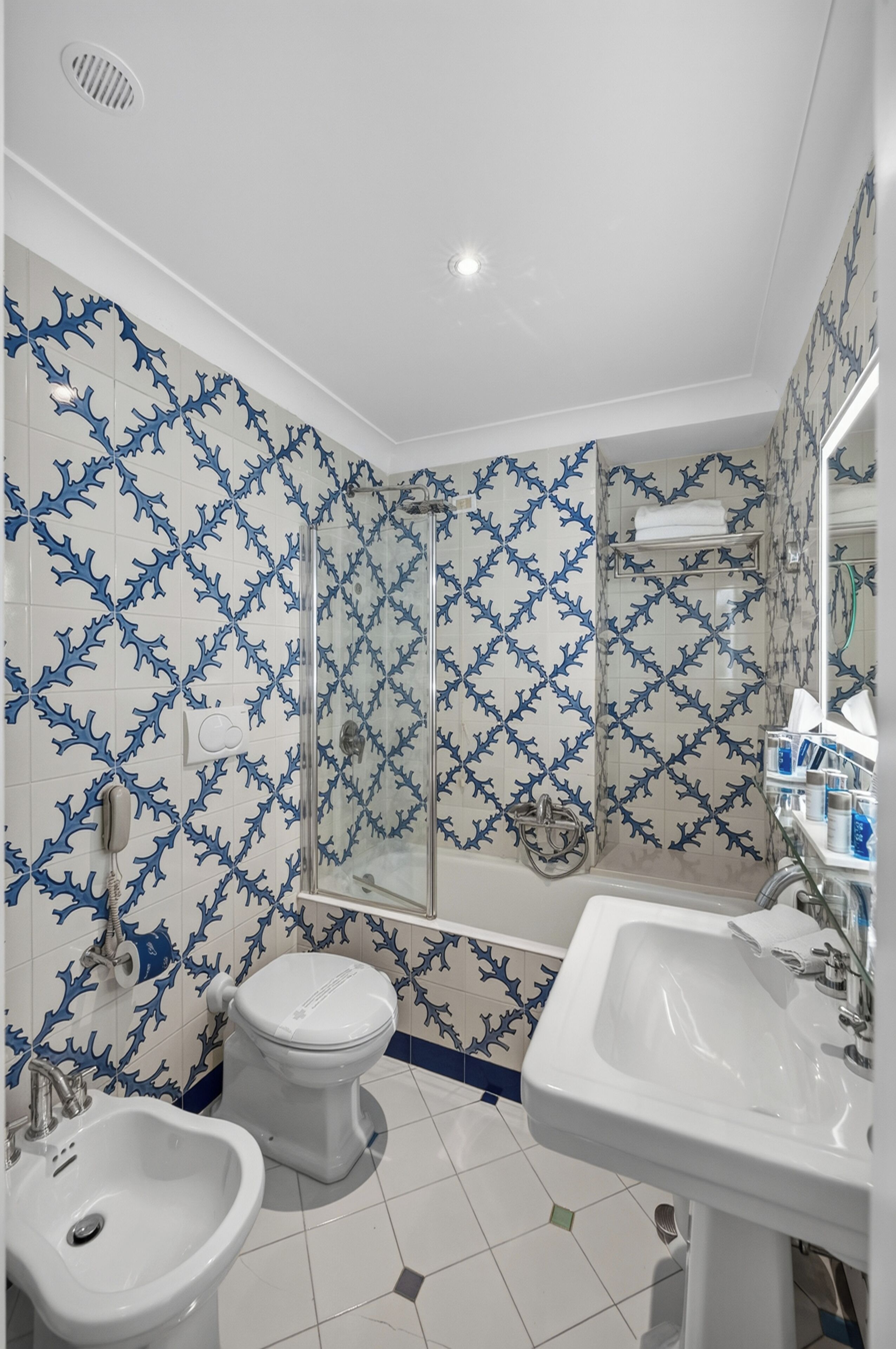 Une salle de bain comprenant des toilettes, un bidet, un lavabo et une douche à parois de verre.
