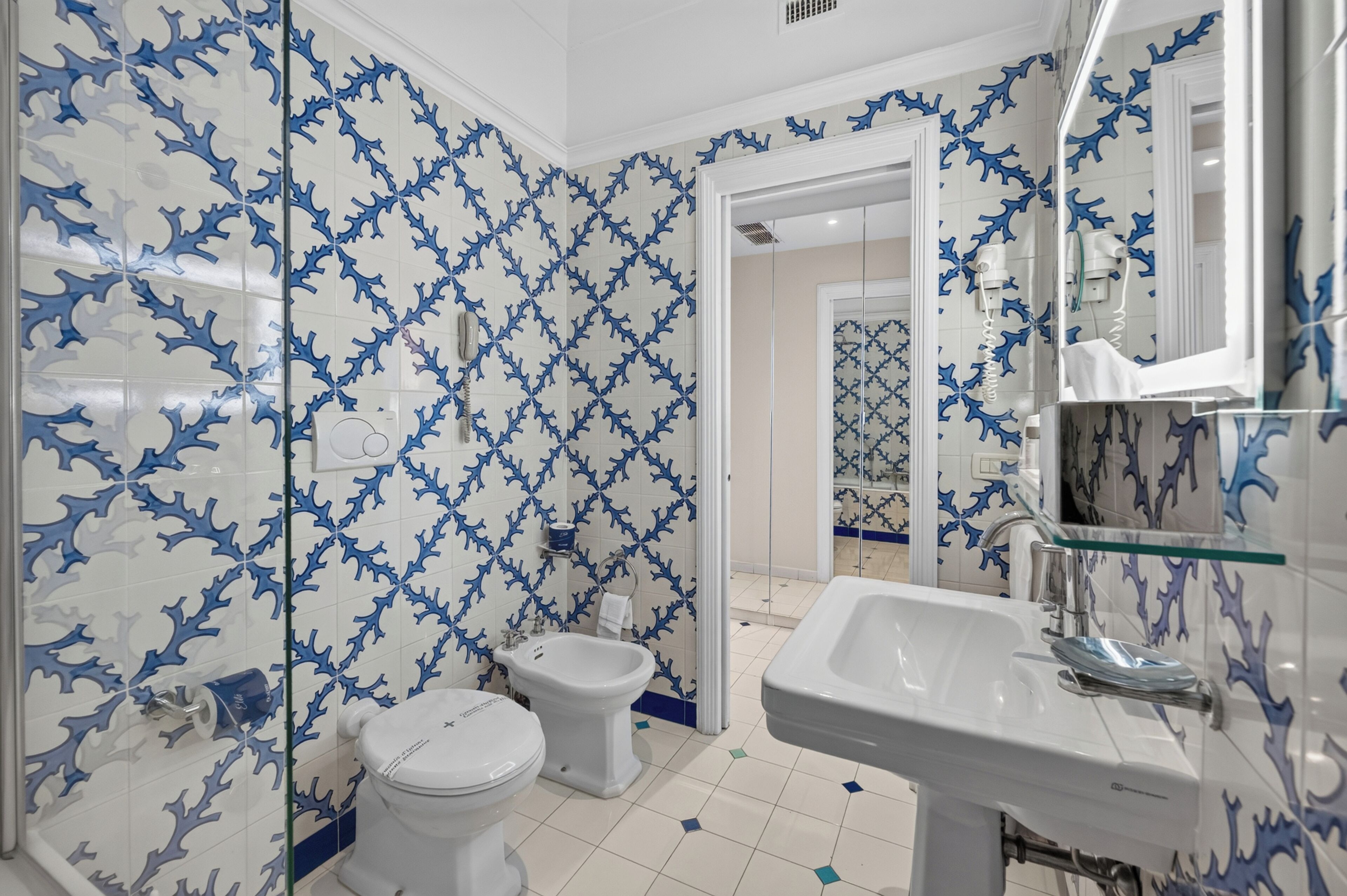 A bathroom with a white sink, a bidet, and a toilet.