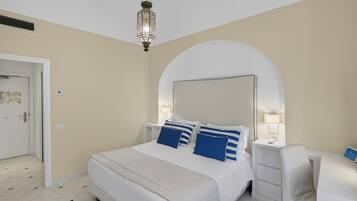 Habitación de hotel con una cama grande, mesitas de noche, un escritorio y una lámpara colgante.