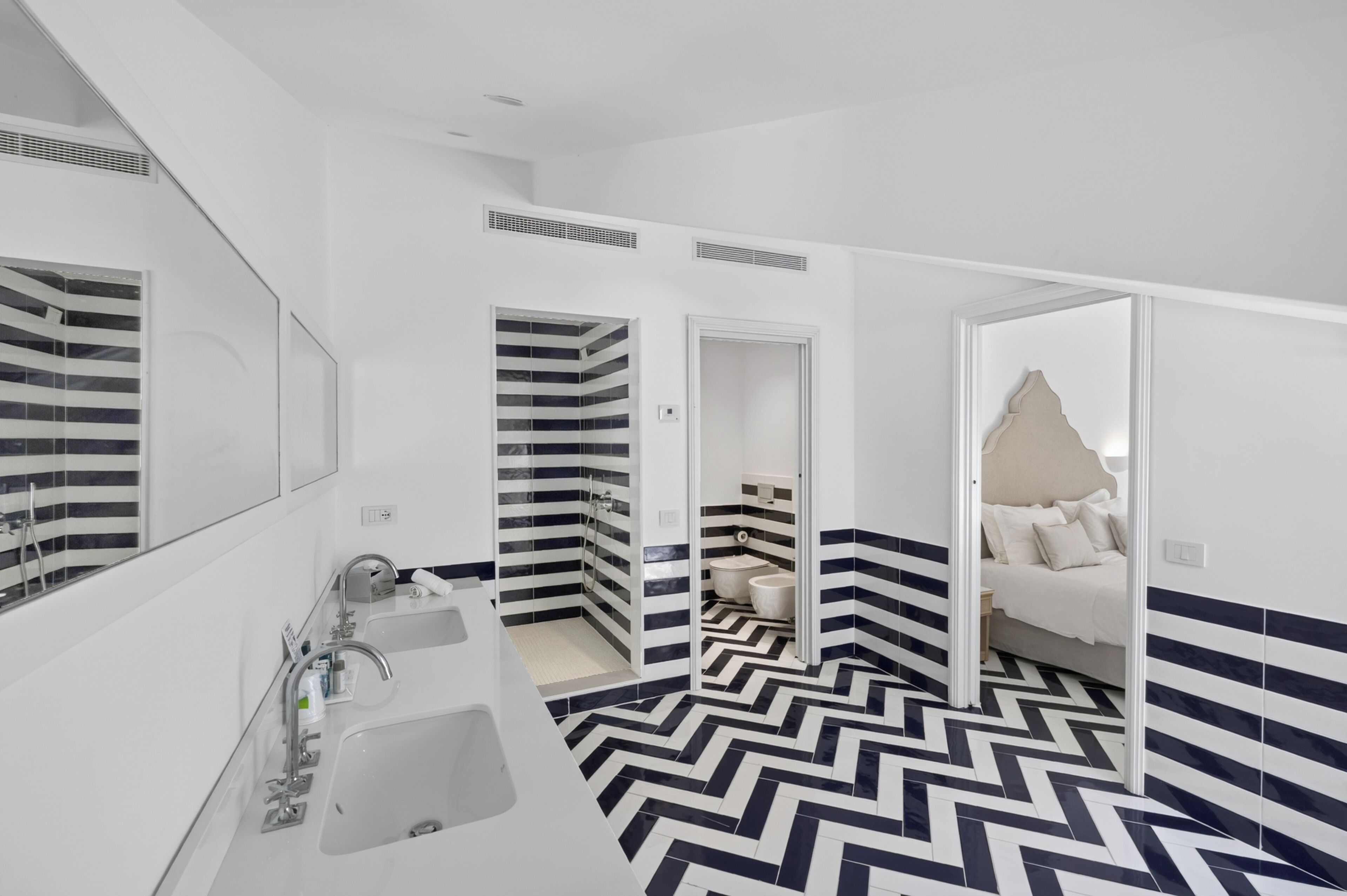 A modern bathroom with a large mirror, two sinks, and a shower.