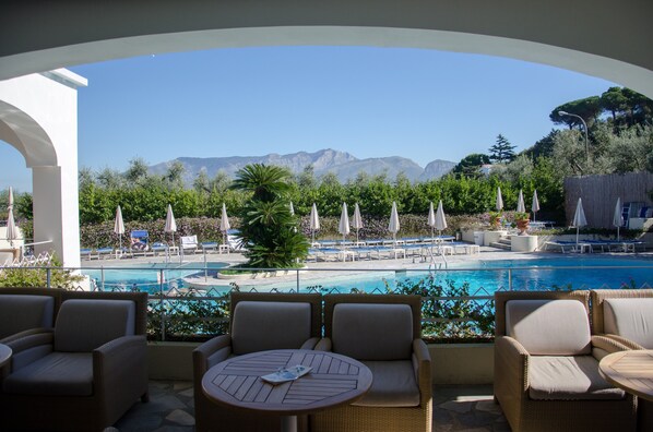 A poolside area with lounge chairs and umbrellas, a pool, and a view of mountains. - Grand Hotel Aminta  (Sorrento)