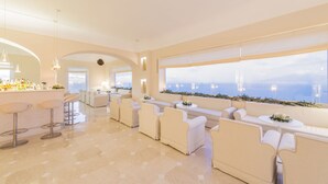 A modern lounge area with bar seating, sofas, and a view of the sea. - Grand Hotel Aminta  (Sorrento)