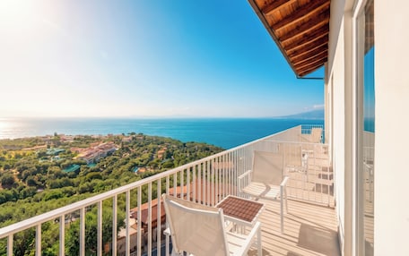 A balcony with a view of the sea and greenery.