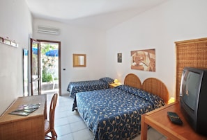 Una habitación de hotel con dos camas, televisión, una mesa y una silla.