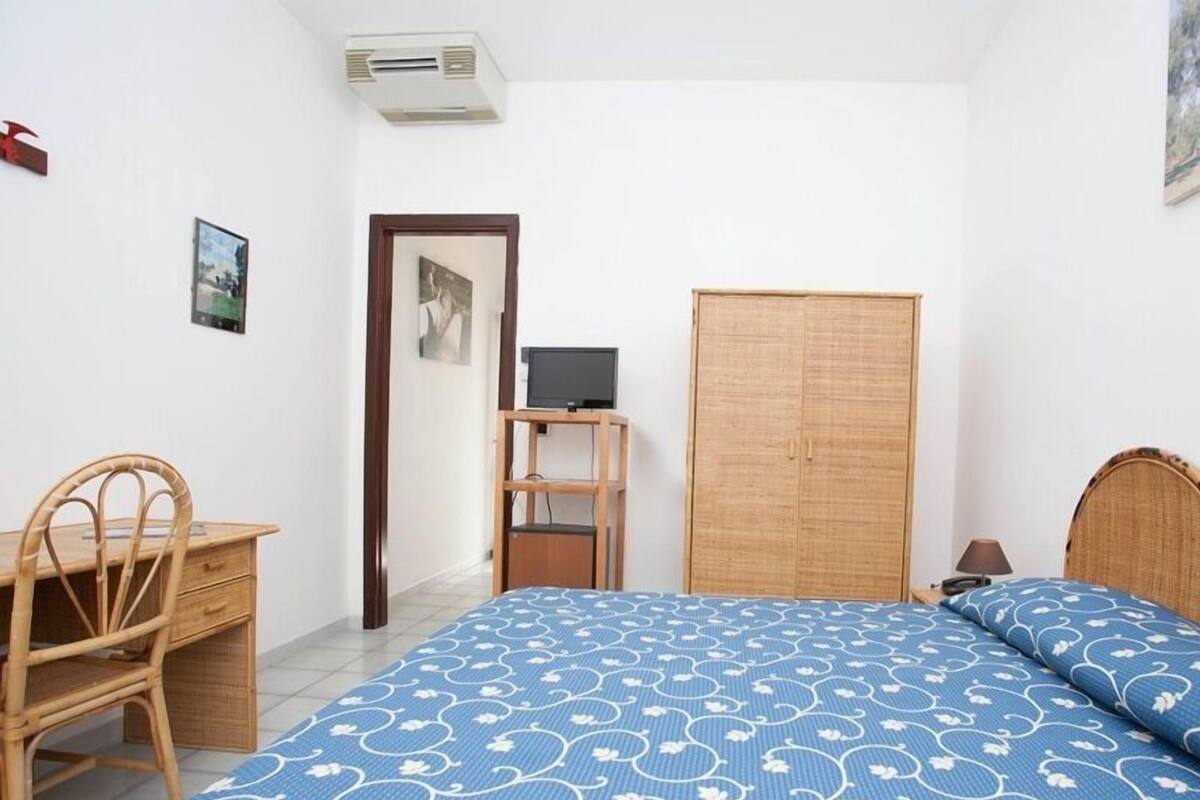 Un dormitorio con cama, escritorio, armario y televisor.
