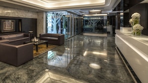 A modern lobby with marble flooring, leather sofas, and a glass partition. - Stanford Hillview Hotel (Kowloon)