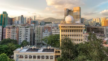 A cityscape with a prominent building featuring a large dome and satellite dishes, surrounded by dense urban high-rises and greenery.