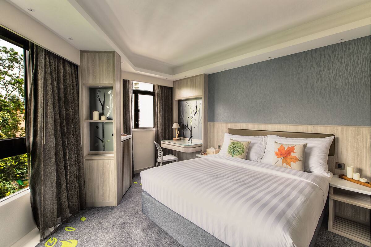 A modern hotel room with a large bed, a desk, and a chair.