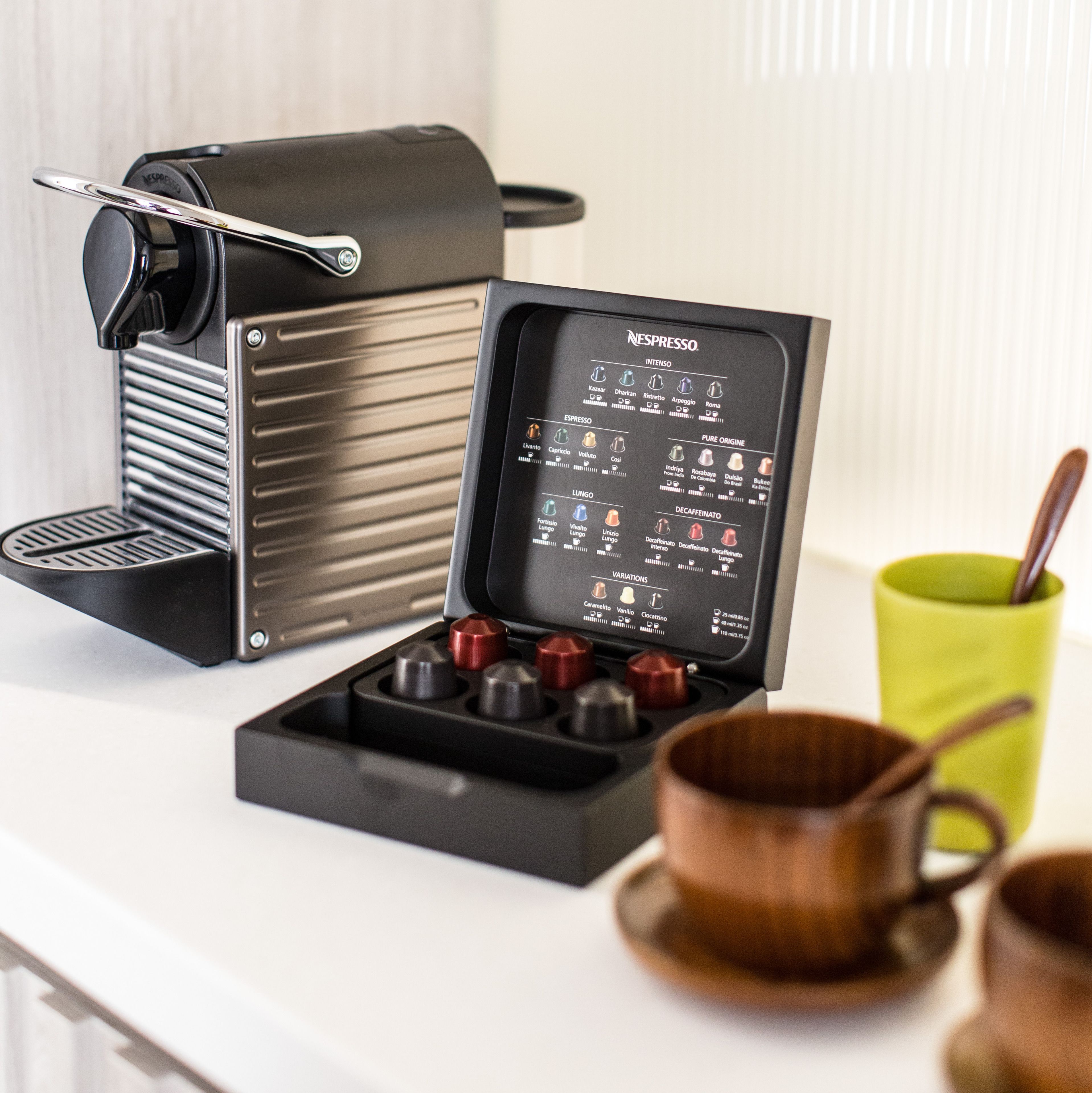 A Nespresso coffee machine with a display panel and a coffee cup on a table.