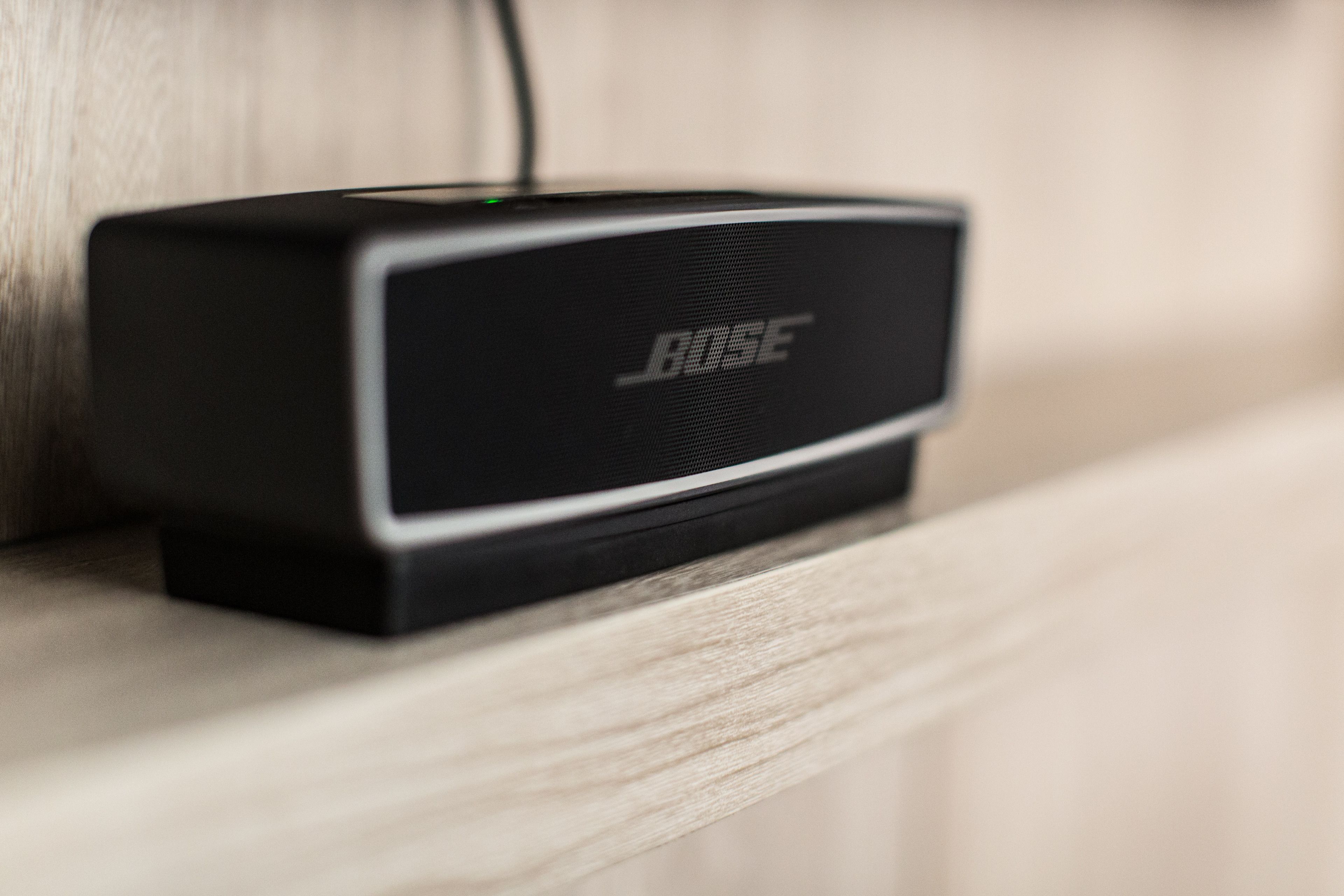 A black Bose speaker on a wooden shelf.