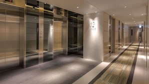 A modern hotel corridor with elevators and a carpeted floor. - Stanford Hillview Hotel (Kowloon)