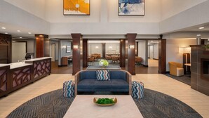 A spacious lobby with a reception desk, a blue sofa with patterned cushions, and a coffee table with a green decorative item. - Homewood Suites by Hilton Columbus/Polaris, OH (Columbus)