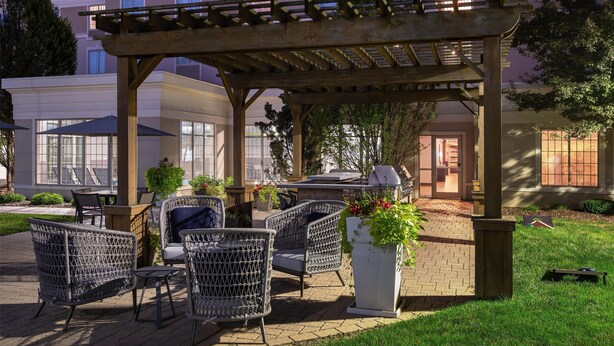 An outdoor patio area with wicker furniture, a pergola, and a brick pathway. - Homewood Suites by Hilton Columbus/Polaris, OH (Columbus)