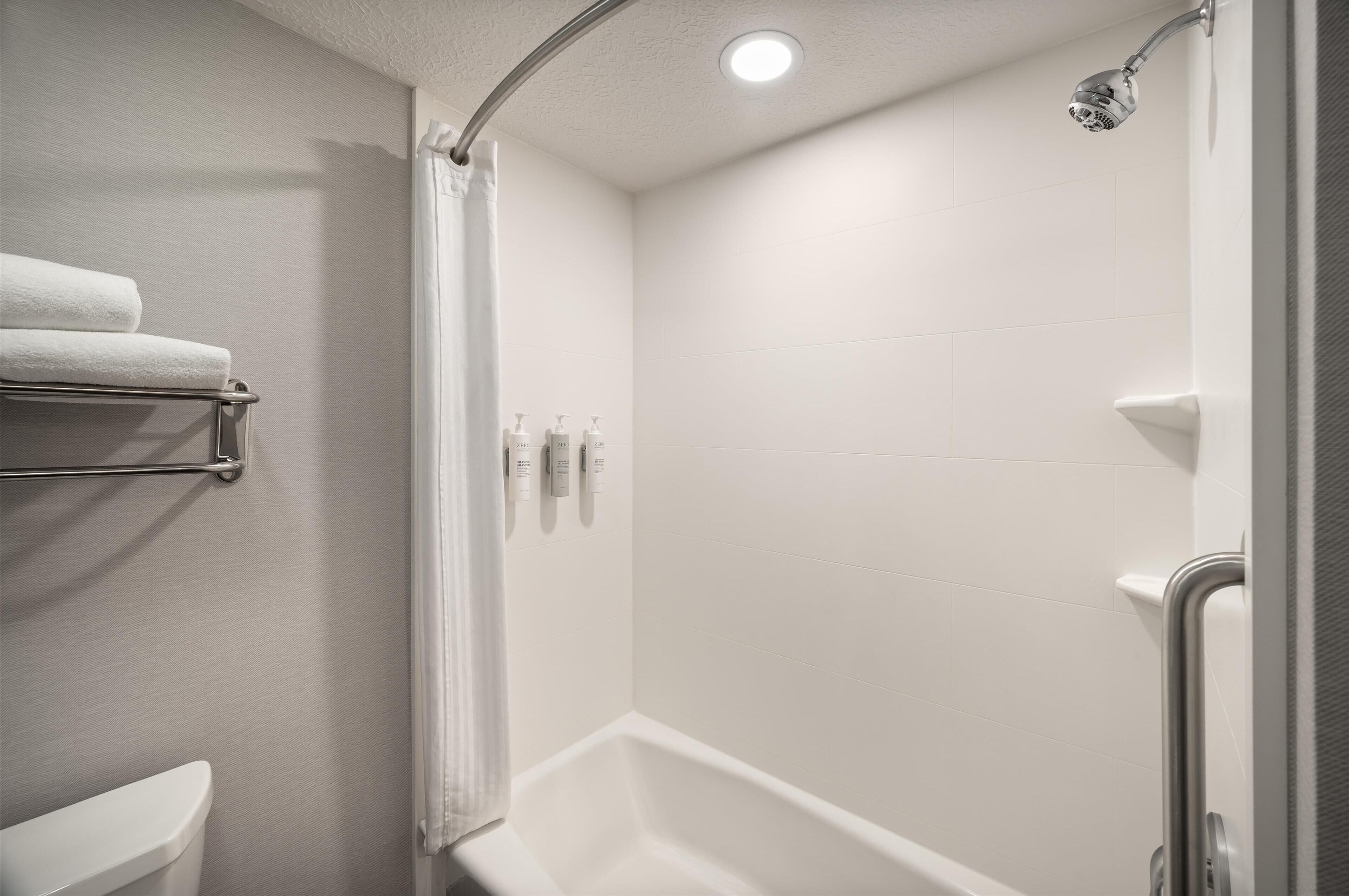 A modern bathroom with a shower, a toilet, and a towel rack.