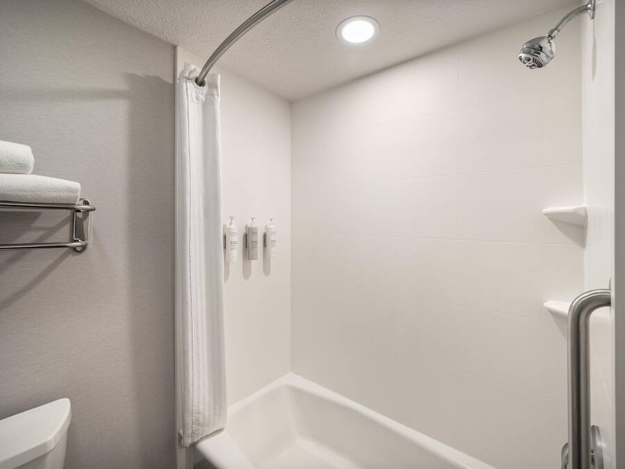 Une salle de bain moderne équipée d’une douche, de toilettes et d’un porte-serviettes.