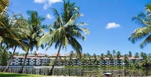 Un resort con piscina, palmeras y un edificio con varios balcones.