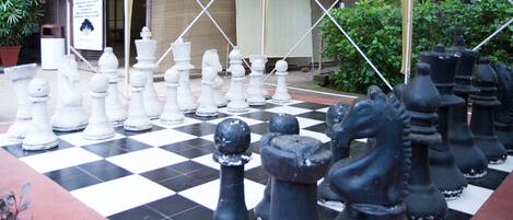 A large outdoor chessboard with chess pieces arranged for a game.