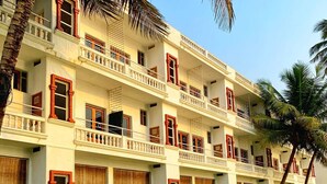 A multi-story hotel with balconies, a well-maintained lawn, and palm trees. - Resorte Marinha Dourada (Arpora)