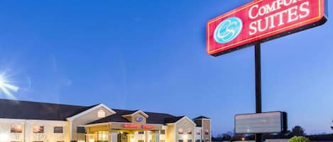 Comfort Suites -hotelli, jossa on suuri, valaistu kyltti, pysäköintialue ja sisäänkäynti.