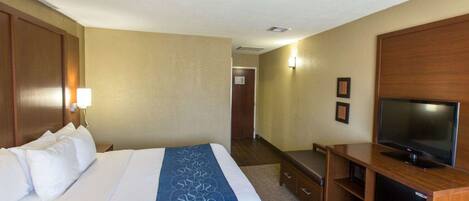 A hotel room with a bed, a TV, a desk, and a wall-mounted TV.