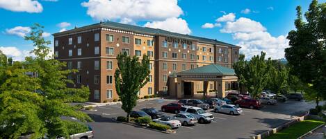 A hotel with a parking lot and a green-roofed entrance.